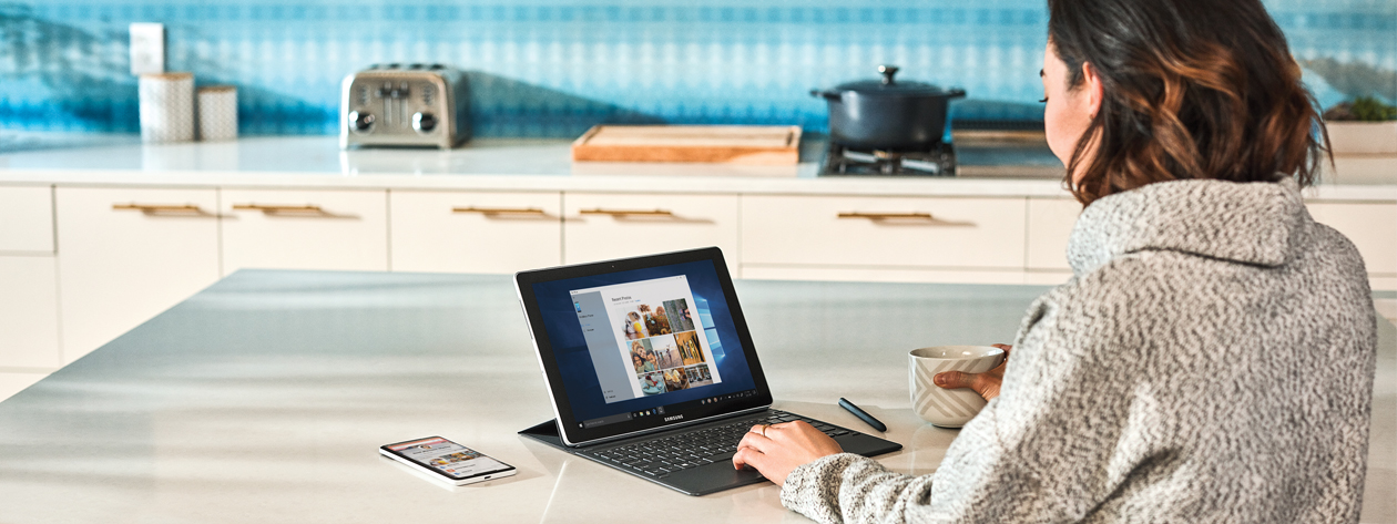 一位女士在厨房中使用 Microsoft Surface 设备的照片。